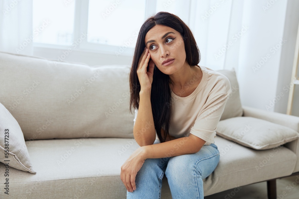 Headache woman sits at home on the couch and touches her head with her hands massage of the temples, high fever in case of illness, migraine Headache woman sits at home on the couch and touches her head with her hands massage of the temples, high fever in case of illness, migraine