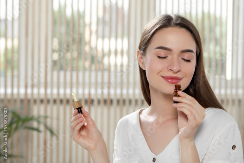Φωτογραφία Young woman smelling essential oil indoors, space for text