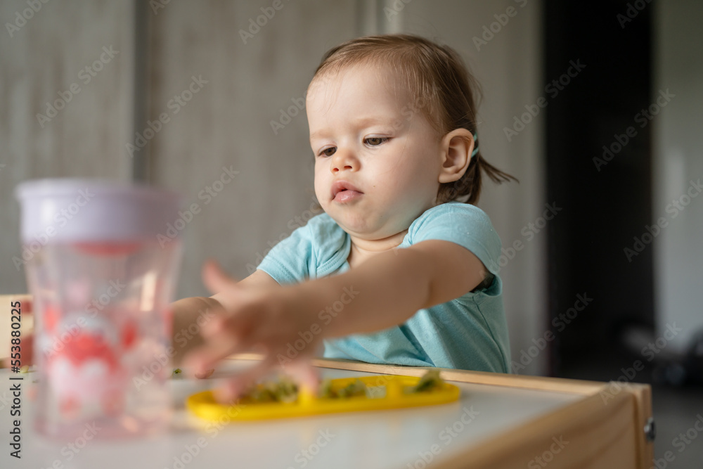 one girl small caucasian child one year old eat at the table at home one girl small caucasian child one year old eat at the table at home