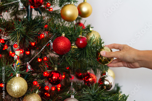 Woman's hand placing golden Christmas ornament