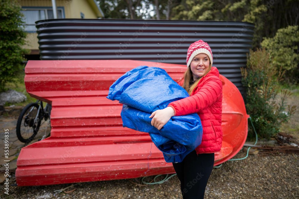woman folding up a tarp at a campground in australia. camping tant and