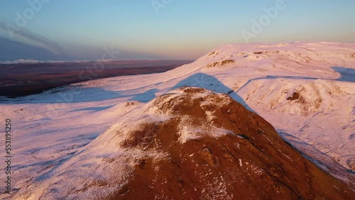 4K Cinematic Aerial Pan Around Snowy Dumgoyne Hill with Hikers on Top. Drone shot during sunset flyover of The Campsies. Campsie Fells near Glagsow photo