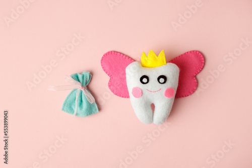Cute toy for Tooth Fairy Day as funny smiling cartoon character of tooth fairy with crown, wings on pink background, copy space flyer, concept children milk toothless, funny toy, handmade felt diy photo