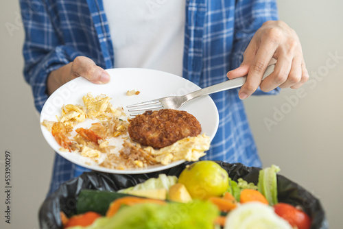 Compost from leftover food, asian young housekeeper woman hand holding cutting board use fork scraping waste, rotten vegetable throwing away into garbage, trash or bin. Environmentally responsible.