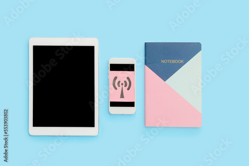 Tablet computer, notebook, mobile phone and paper sheet with WiFi symbol on color background