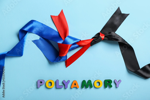 Фотография Word POLYAMORY with ribbons on blue background