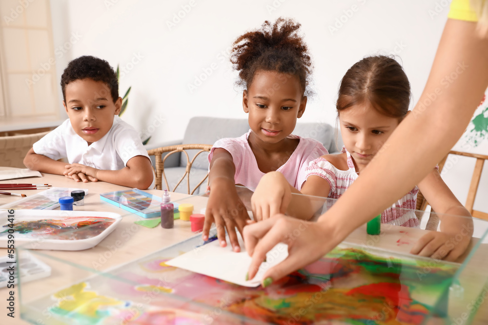 Little children with teacher marbling paper in workshop for Ebru painting Little children with teacher marbling paper in workshop for Ebru painting