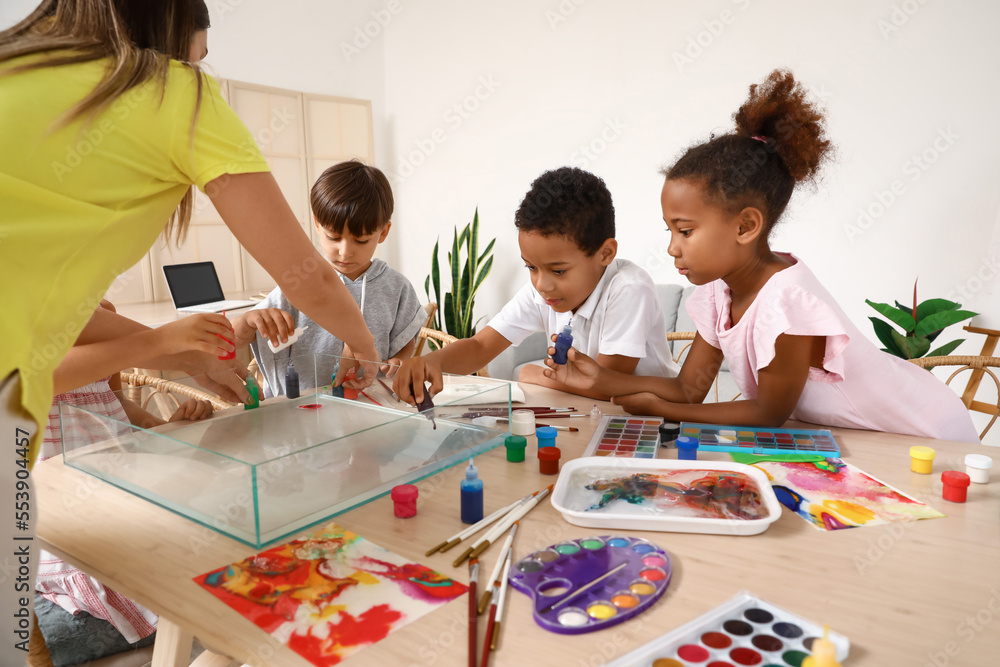 Fototapeta premium Little children with teacher painting on water during master class in Ebru at workshop