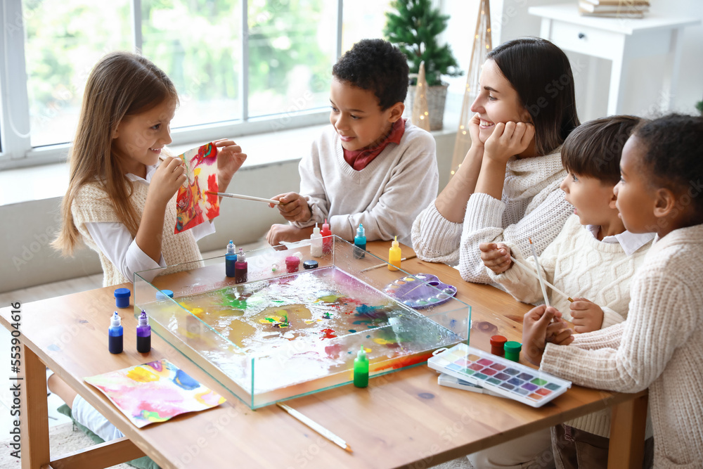 Little children with teacher during master class in Ebru painting on Christmas eve