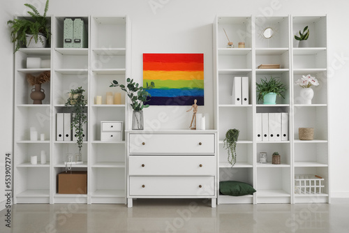 Interior of light room with rainbow painting, chest and shelving units © Pixel-Shot