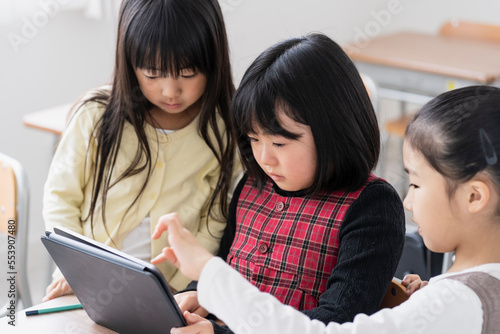 教室でタブレットPCを見る日本人小学生