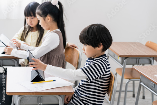 教室でタブレットPCを見る日本人小学生