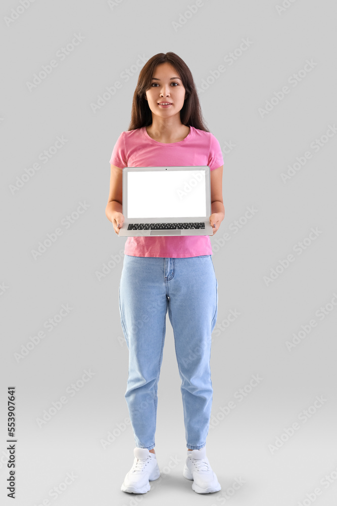 Young Asian woman with laptop on light background Young Asian woman with laptop on light background