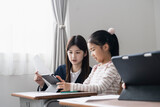 タブレットPCを使った授業をする日本人小学生の女の子と女性教師