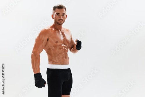 Man athletic bodybuilder poses in boxing gloves with nude torso abs in full-length background, boxing and martial arts. Advertising, sports, active lifestyle, competition, challenge concept.  © SHOTPRIME STUDIO