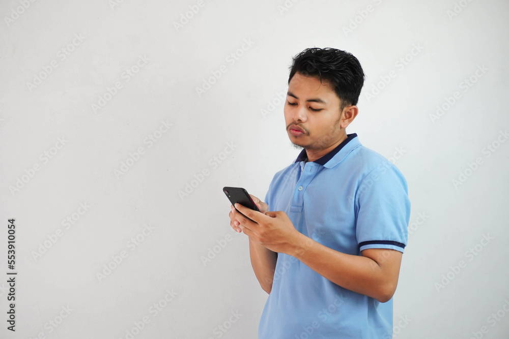 expression of dislike trying to dodge with holding phone young asian man wearing blue polo t shirt isolated on white background expression of dislike trying to dodge with holding phone young asian man wearing blue polo t shirt isolated on white background