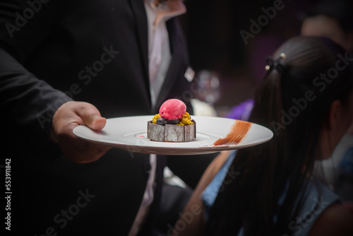 Butler holding plate of fine fancy sherbet on his right hand prepare put on the table