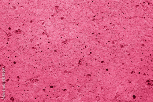 Wall of concrete with pores in trend color of the 2023 viva magenta.