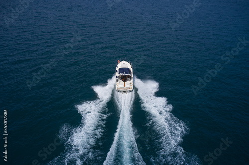 Big white yacht movement on the water top view. Yacht in the sea aerial view. Aerial view of the sea and the boat.