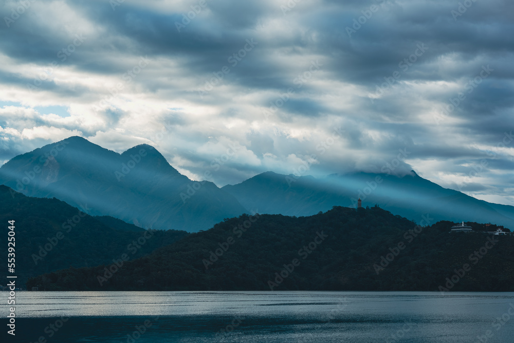 Mountains surrounded by clouds. Crepuscular Ray shines on the village. Chaowu Pier, Sun Moon Lake National Scenic Area. Nantou County, Taiwan