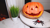 Carved pumpkin face with a black spider on the table