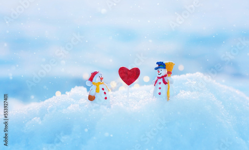 two snowman toy with heart on snow close up  natural winter background. Christmas and New Year holidays. Valentine s Day concept. festive winter season