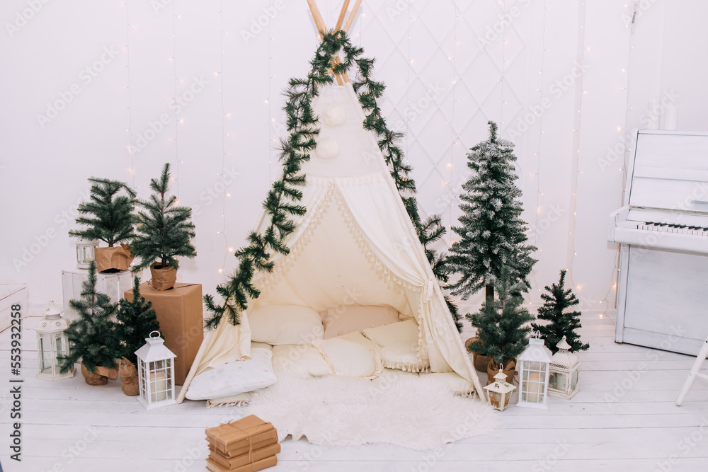 Christmas wigwam. Hall room with cozy atmosphere with Christmas trees and a lot of pillows in beige, gold and white colors. Сelebration of New Year. No people	