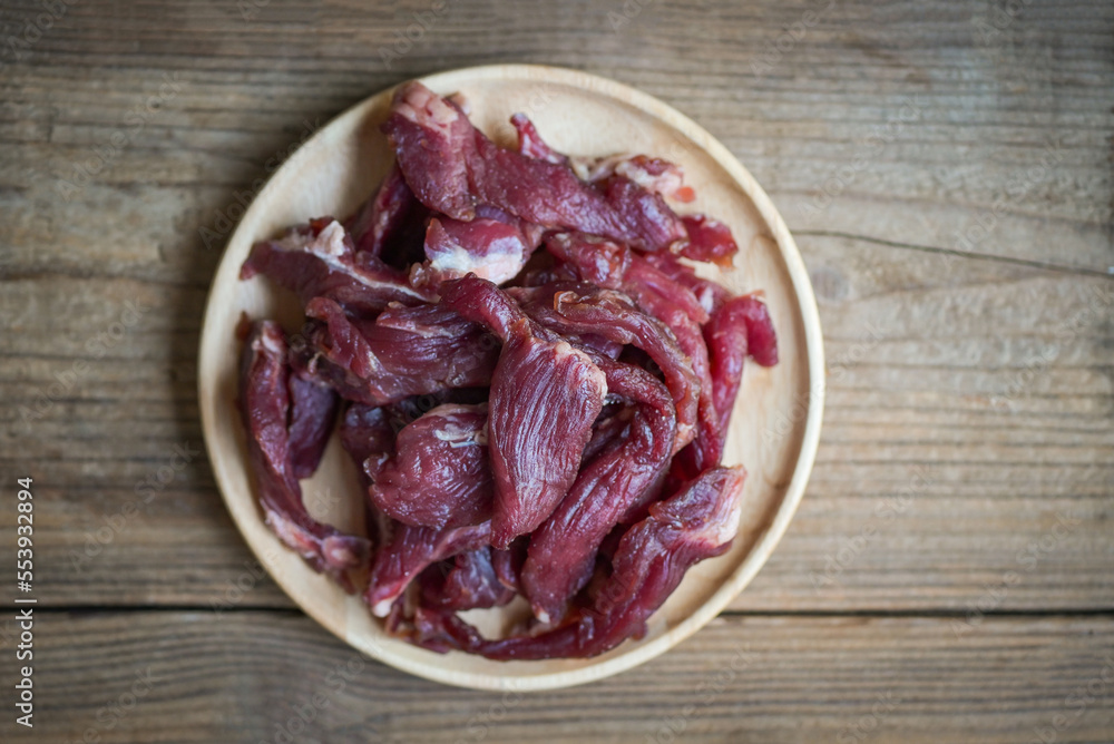 beef jerky on wooden plate, raw dried meat for cooking, dry meat beef in Thailand food - top view