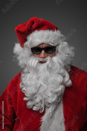 Portrait of stylish santa claus with sunglasses isolated on grey background.
