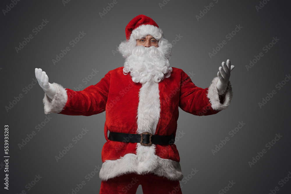 Studio shot of friendly old santa with glasses and beard isolated on gray background.