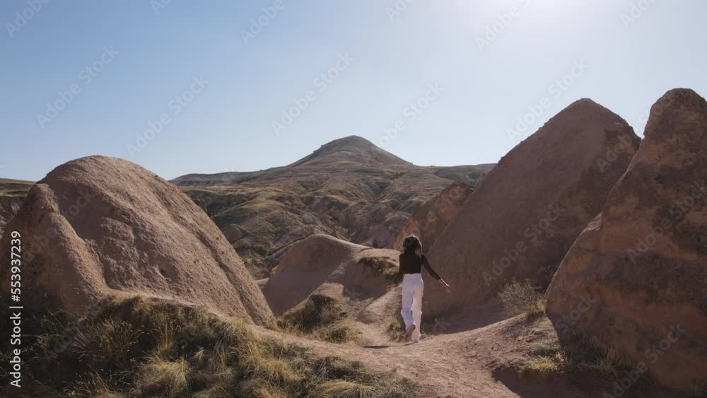 Back view of Young girl running in Valleys of Cappadocia, Mountains, Sunset view