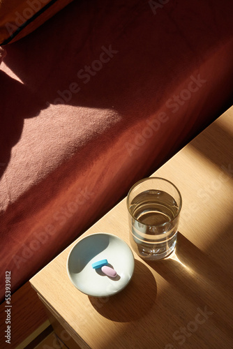 Vitamins and a glass of water on the bedside table in the morning