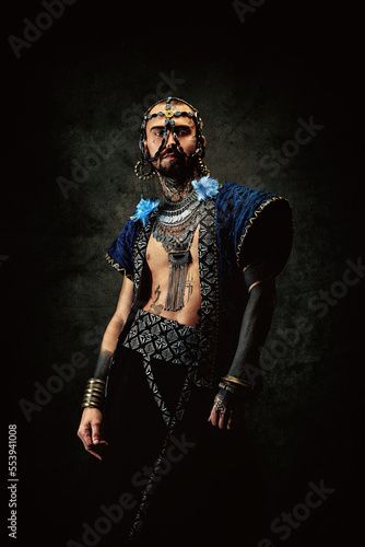 Tattooed bearded man, wearing ethnic clothing and jewelry