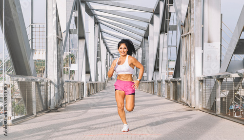 middle-aged female athlete running across a bridge