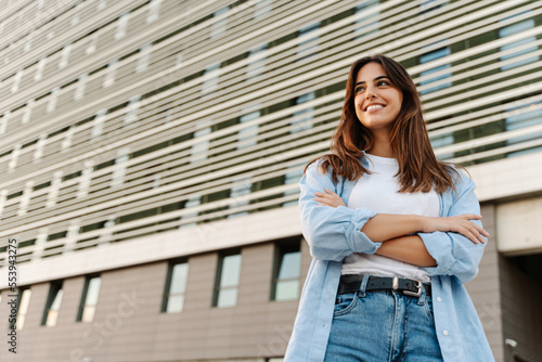 Canvas-taulu Portrait confident young woman standing in the city looking to the side with hap