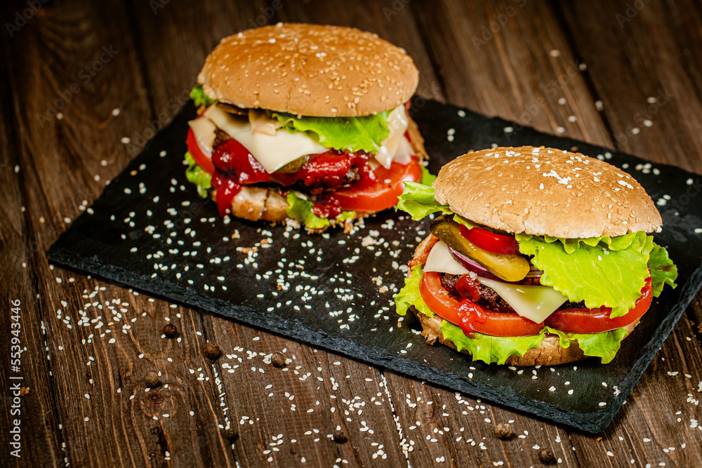 From above view of delicious burgers with beef, cheese, tomato, lettuce on board. Selective focus From above view of delicious burgers with beef, cheese, tomato, lettuce on board. Selective focus