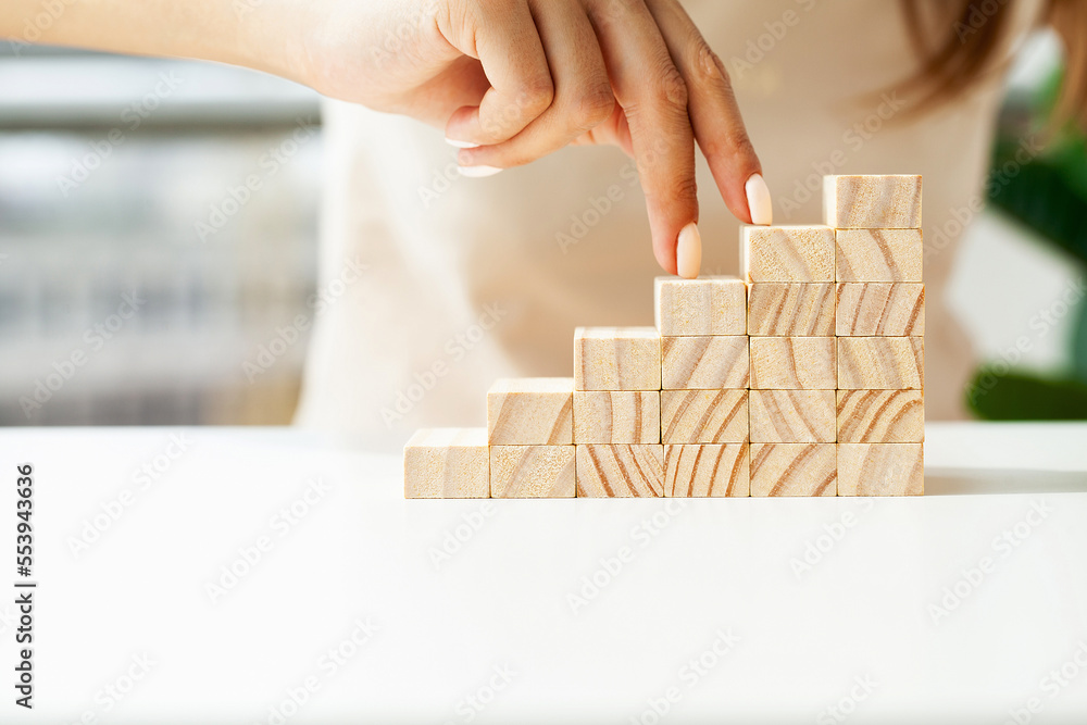 Woman hand stepping up wood block stacking as step stair
