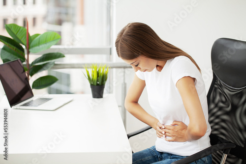 Young woman holding her stomach, she is having a menstruation pain.