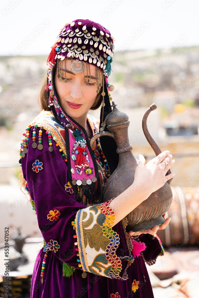 beautiful girl in Turkish national clothes with a teapot in her hands.