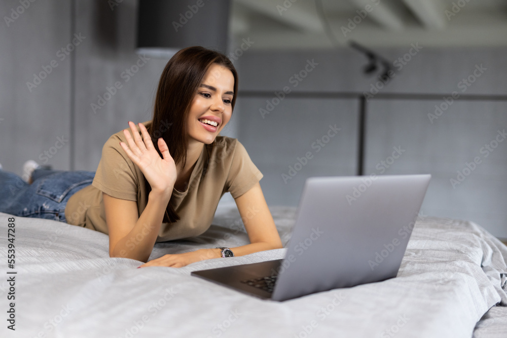Young woman working form home with laptop and waving hand on a video call Young woman working form home with laptop and waving hand on a video call