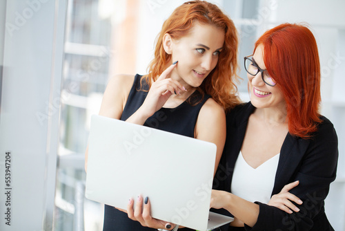 Two red-haired woman work together in the modern office