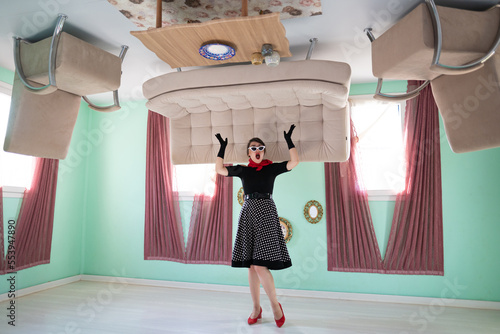 Cuadro en lienzo a girl retro style, surprised, in an upside-down house, as well as furniture placed on the up