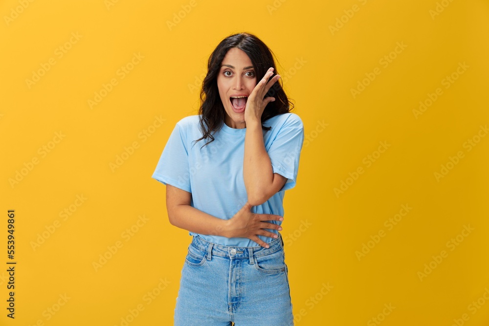 Woman signal smile with teeth emotion portrait in blue t-shirt on yellow background, hands up, surprise, lifestyle, copy space Woman signal smile with teeth emotion portrait in blue t-shirt on yellow background, hands up, surprise, lifestyle, copy space