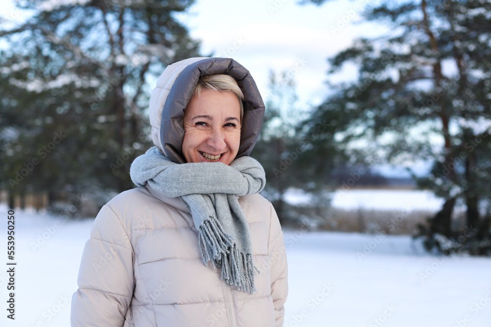Obraz premium Portrait of happy beautiful elderly senior retired woman in age is playing, having fun with snow outdoors in forest or park at winter cold day, smiling, enjoy weather