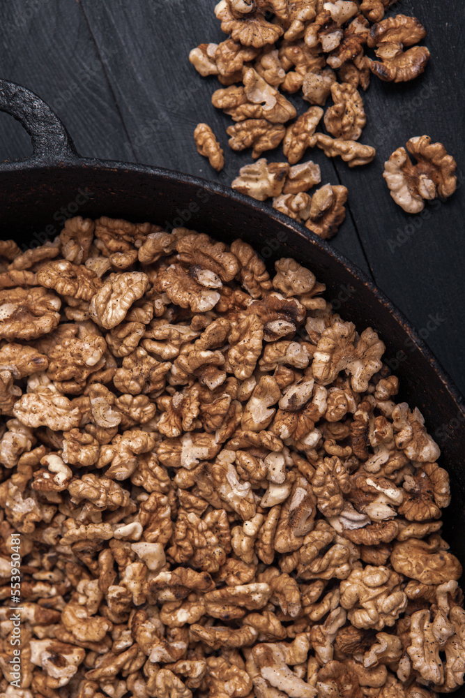 Walnut background. Peeled walnuts on a iron plate on black. walnuts a real super food full of vitamins and vegetable fats Walnut background. Peeled walnuts on a iron plate on black. walnuts a real super food full of vitamins and vegetable fats
