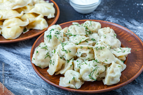 Traditional russian pelmeni or ravioli, dumplings with meat on wood black background. Russian food and russian kitchen concept.