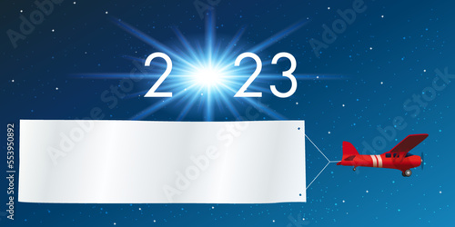 Carte de vœux 2023 montrant un avion rouge tirant une banderole blanche pour souhaiter la bonne année, devant un ciel étoilé.