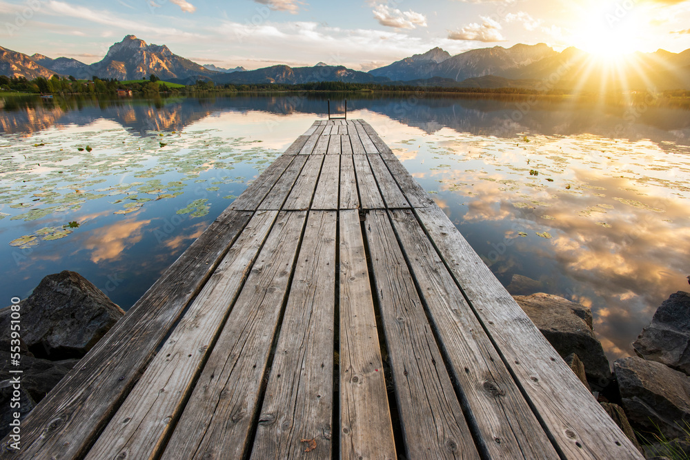  jetty and wooden pier over lake with mountain range in sunset