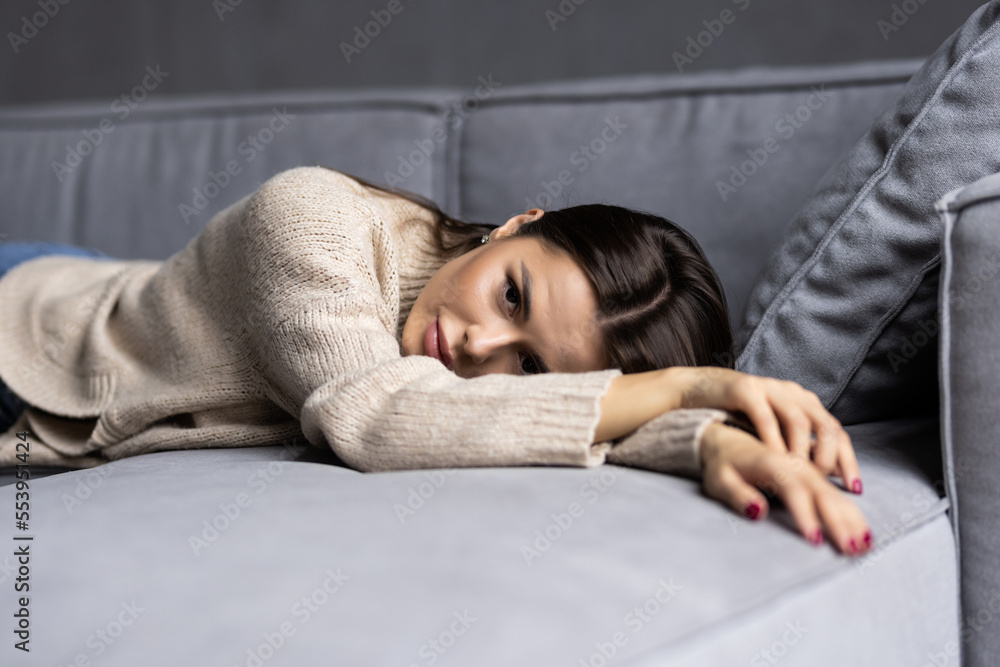 Smiling young woman dreaming about summer leisure while sitting with closed eyes and hands behind head on sofa at home. Smiling young woman dreaming about summer leisure while sitting with closed eyes and hands behind head on sofa at home.
