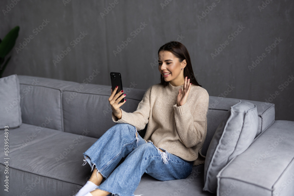 Happy woman waving hand using smartphone app enjoying online virtual chat video call with friends in distance mobile chat virtual meeting, recording stories for social media at home. Happy woman waving hand using smartphone app enjoying online virtual chat video call with friends in distance mobile chat virtual meeting, recording stories for social media at home.